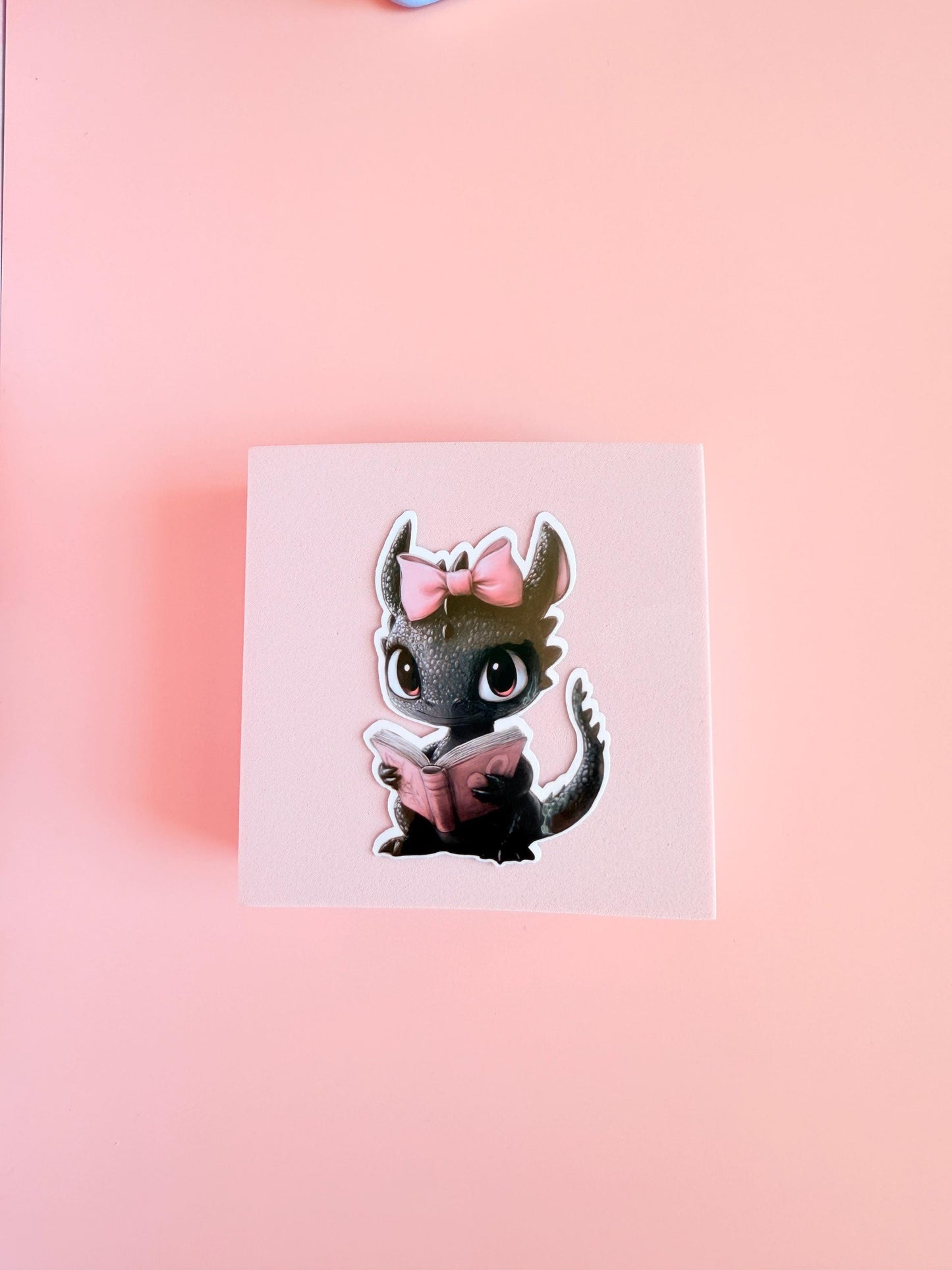 sweet little black dragon with pink coquette bow and valentines day book.
