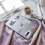 Grey tablet decorated with Powerless-inspired romantasy stickers on a purple throw with coffee and lavender, by The Sticker Era
