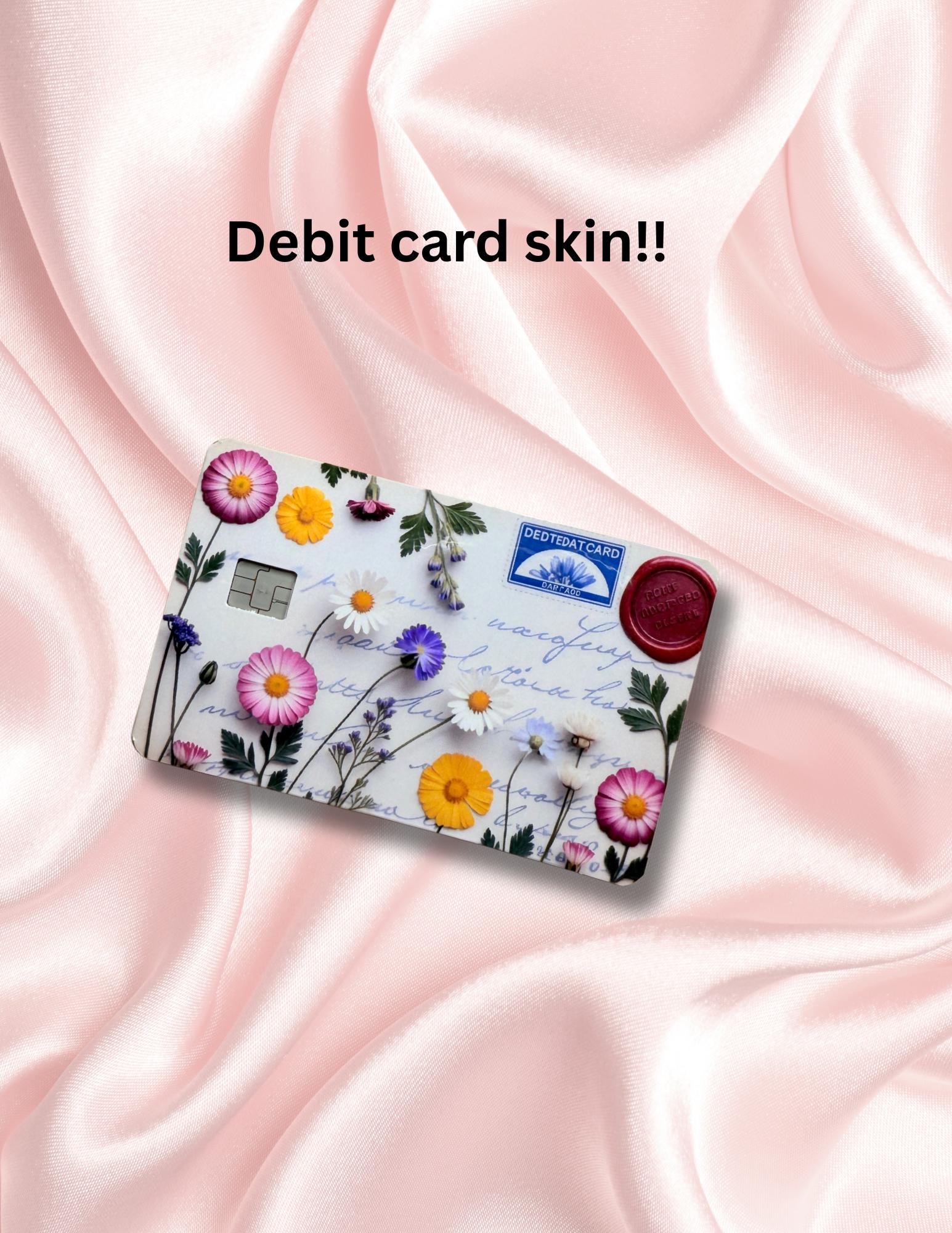 Beach-themed debit card skin with an illustration of an open book, coffee cup, seashells, and ocean waves. Displayed on a pastel pink background with soft floral graphics. Ideal for book lovers, beach vibes, and dreamy aesthetic fans looking for a vinyl card cover or cute credit card sticker.