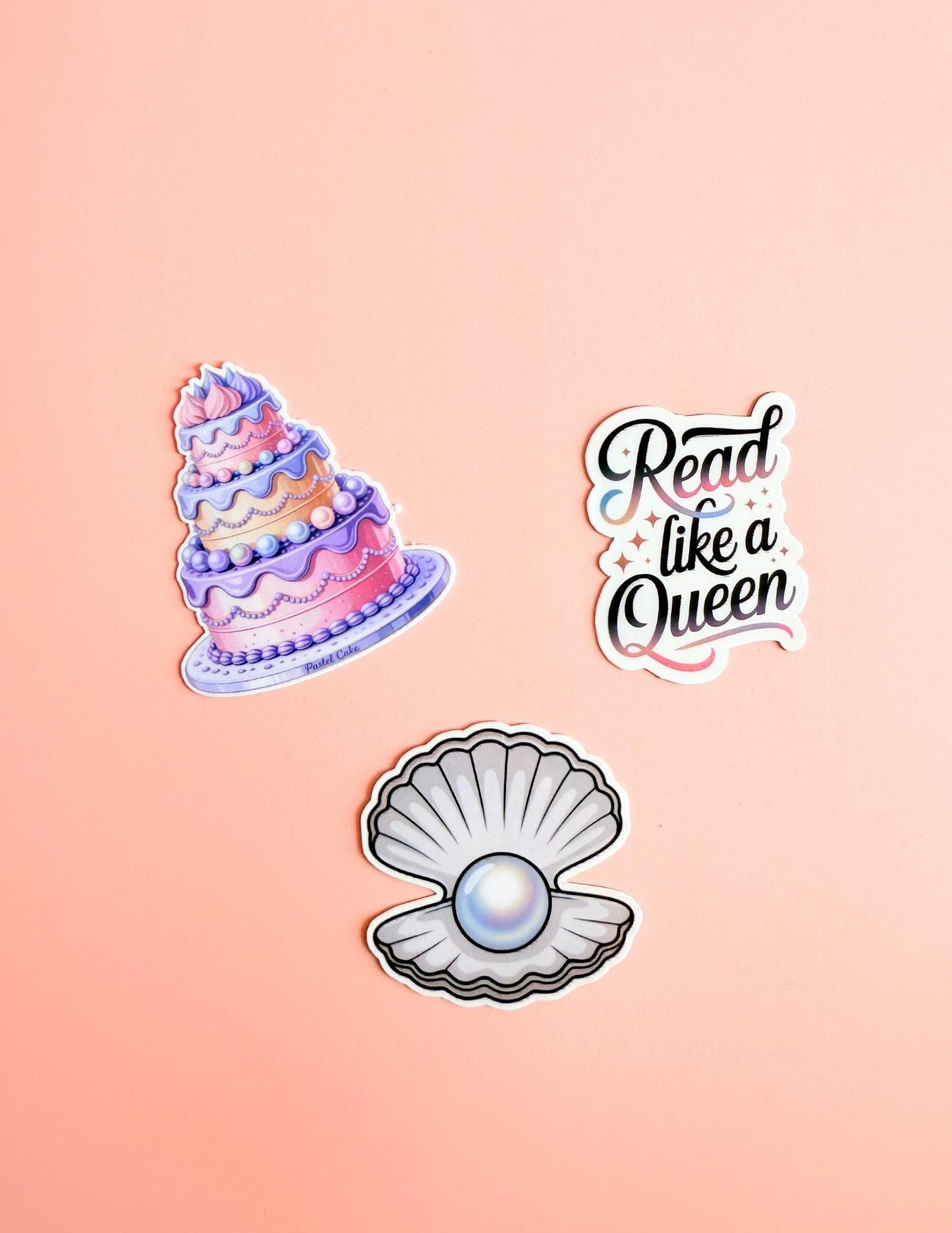 A whimsical sticker set featuring a slice of cake, a smiling clam, and a book quote that says “Read Like a Queen.” Bright, dreamy vinyl stickers with playful fantasy vibes, perfect for book lovers and cozy aesthetic fans.
