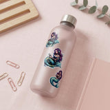 purple haired mermaid stickers, one reading, one listening to audio, and one hugging a book placed on a glass water bottle laying on a desk with pink closed journal
by the sticker era
