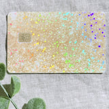 Sparkly gold glitter card skin laid flat with eucalyptus and confetti by The Sticker Era