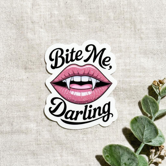 Vampire romance vinyl sticker with pink lips and fangs reading Bite Me Darling by The Sticker Era