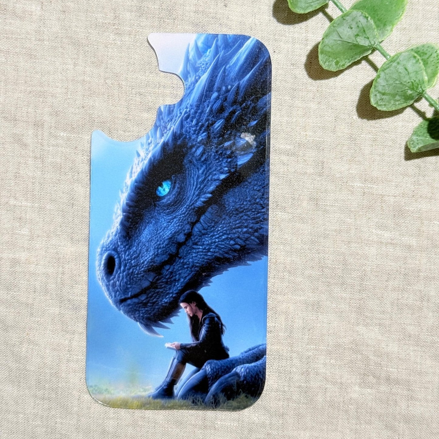 Blue dragon phone insert with a luminous dragon over a reading girl on a clear iPhone case styled with eucalyptus by The Sticker Era