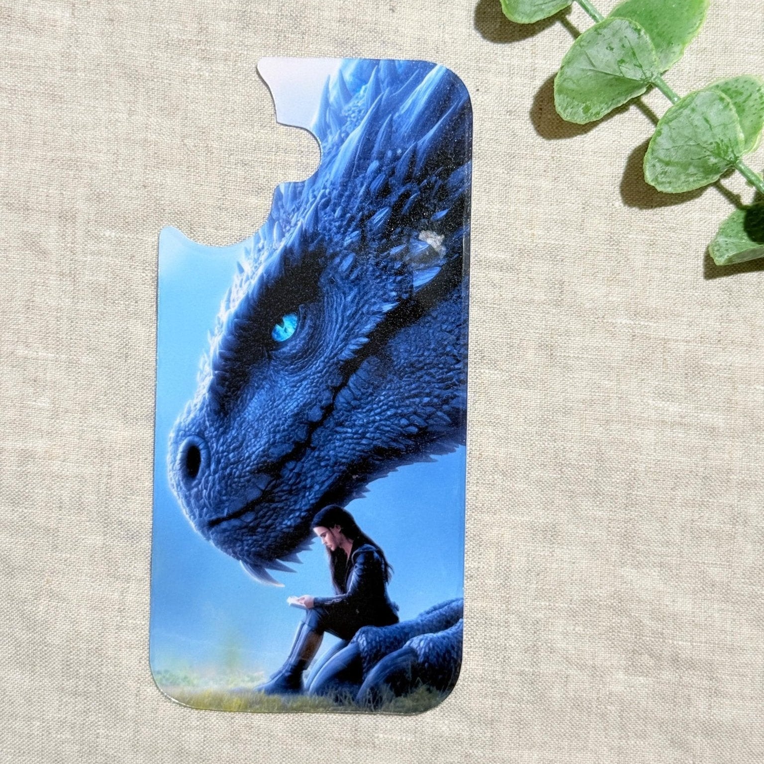 Blue dragon phone insert with a luminous dragon over a reading girl on a clear iPhone case styled with eucalyptus by The Sticker Era