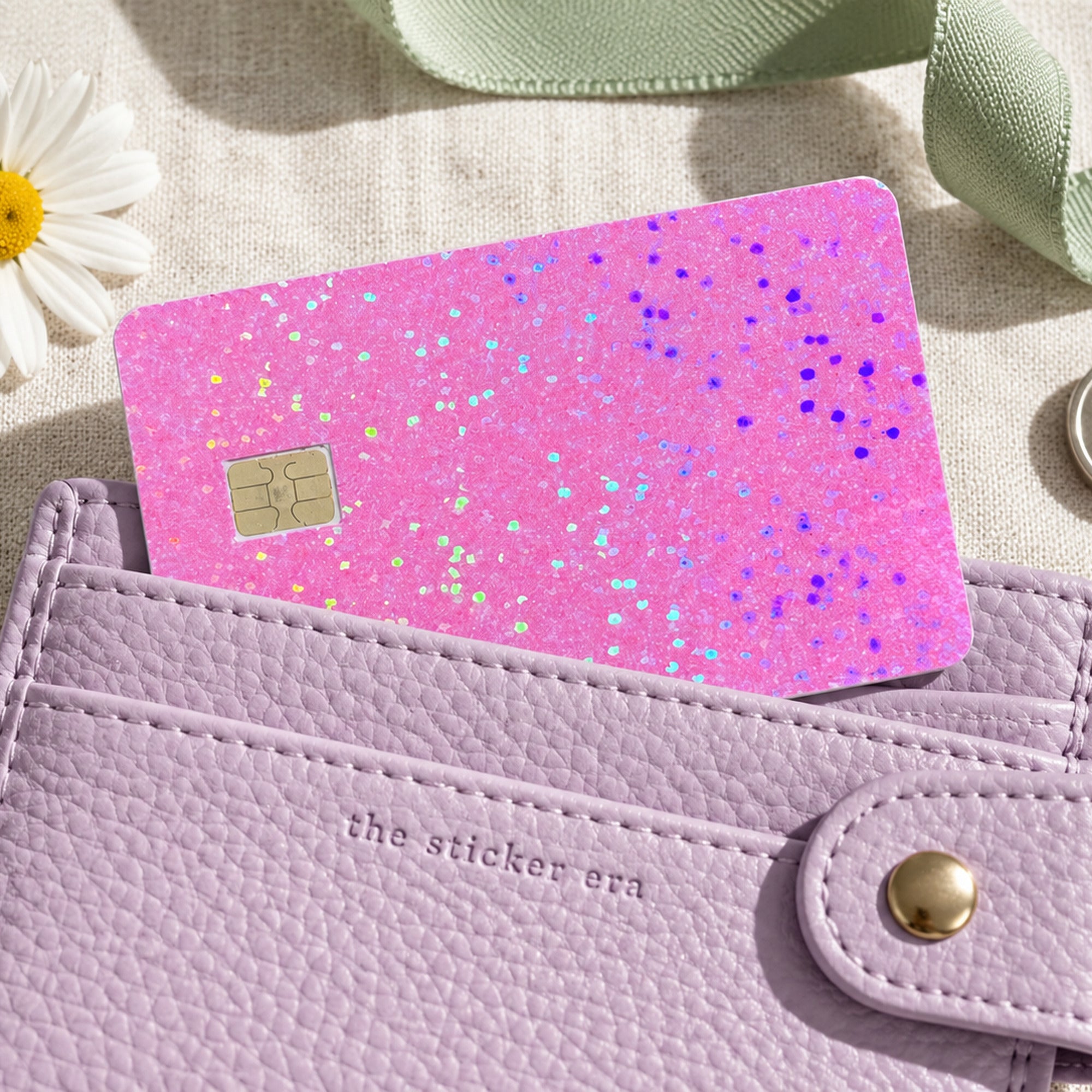 Pink glitter card skin tucked into a lilac card wallet with keys and a daisy by The Sticker Era
