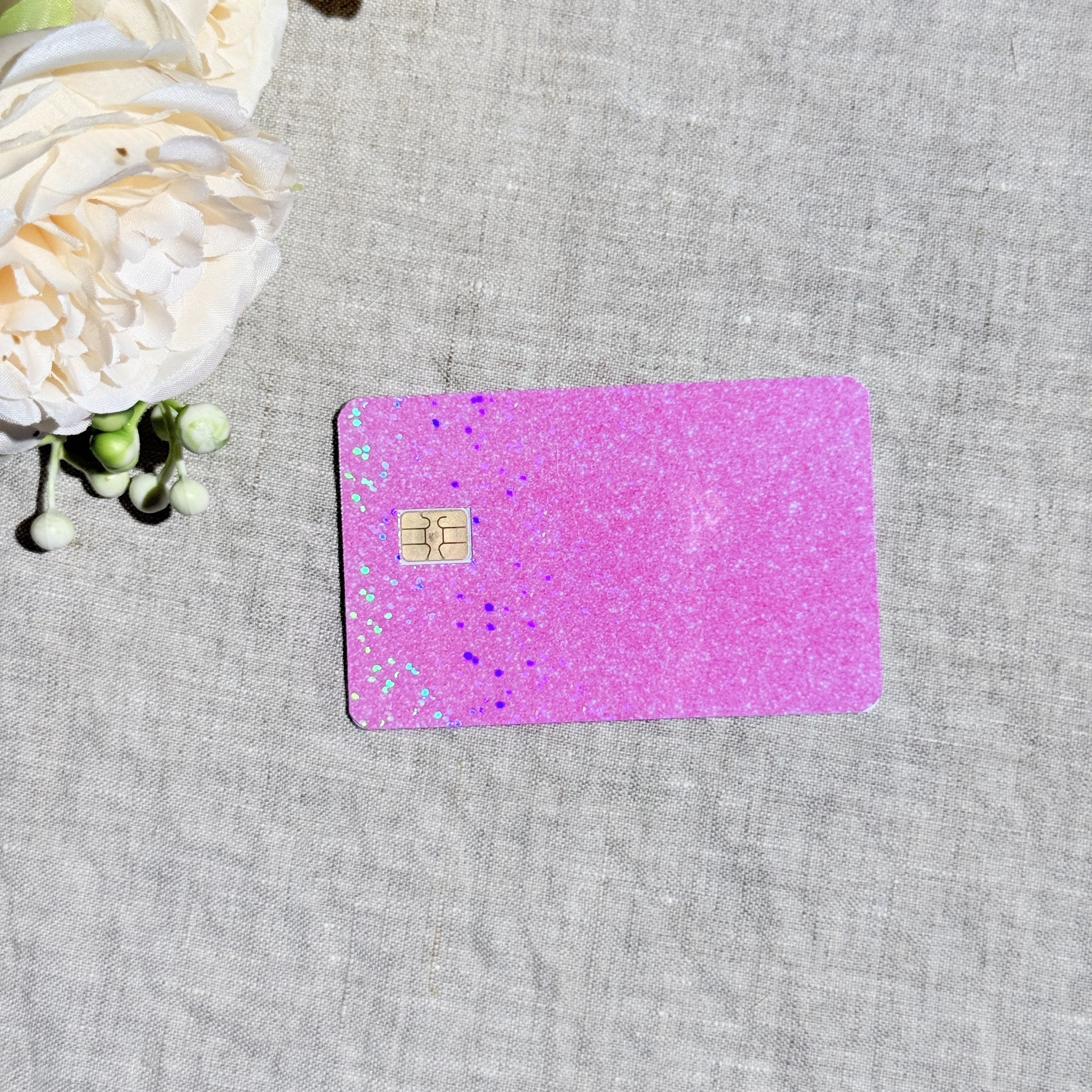 Light pink glitter debit card skin flat lay on cream linen by The Sticker Era