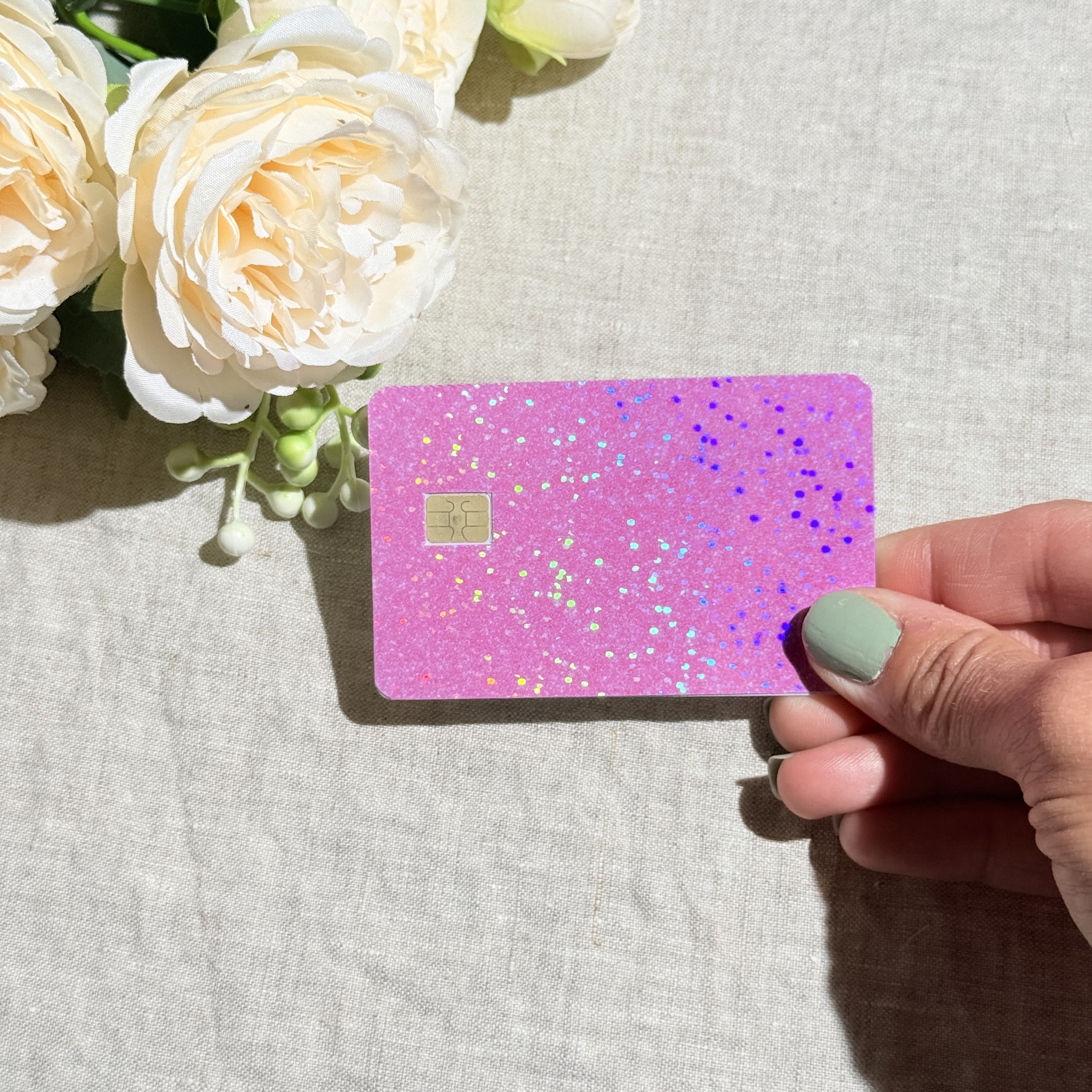 Light pink glitter credit card sticker held up in sunlight by The Sticker Era