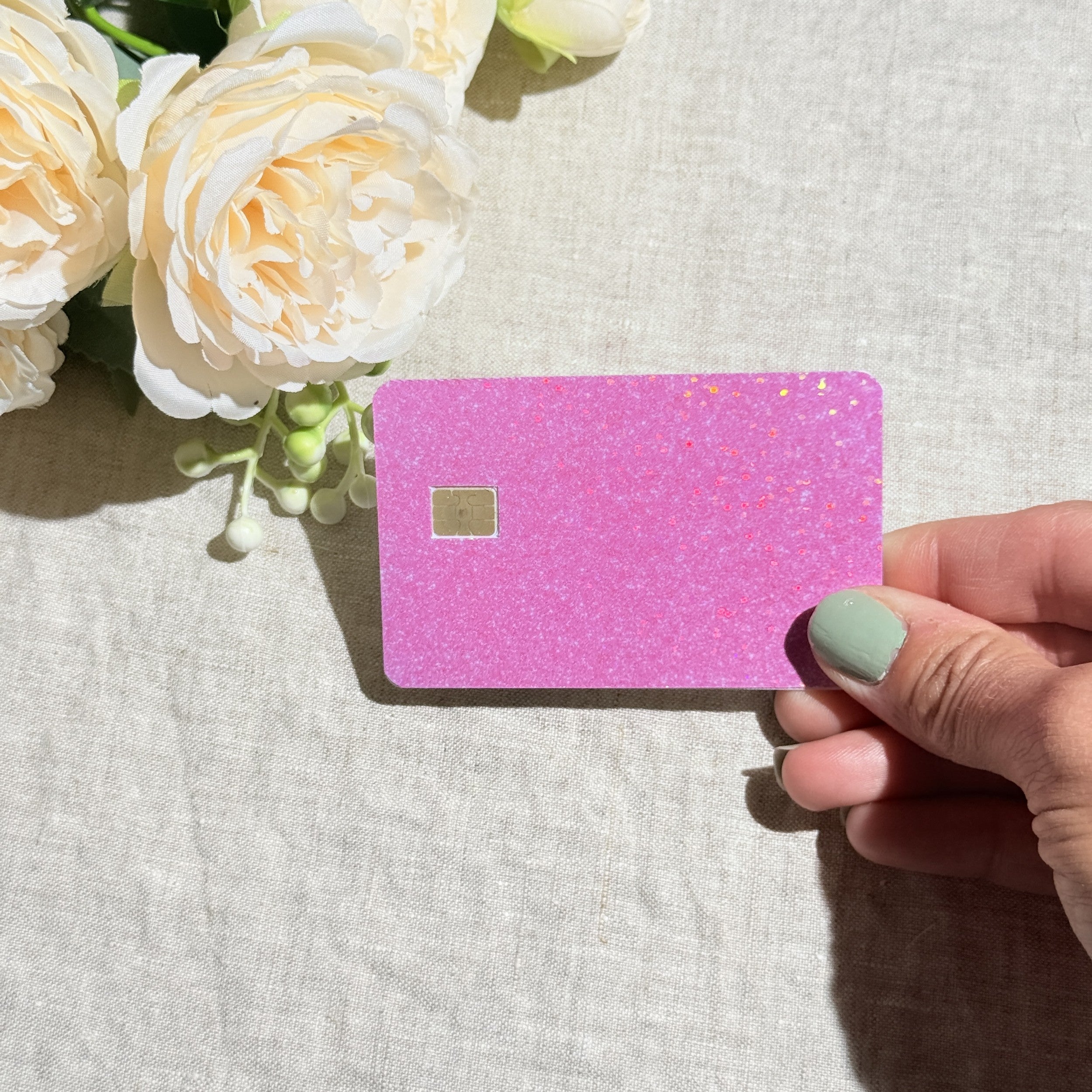 Pastel pink glitter card skin held at an angle by The Sticker Era
