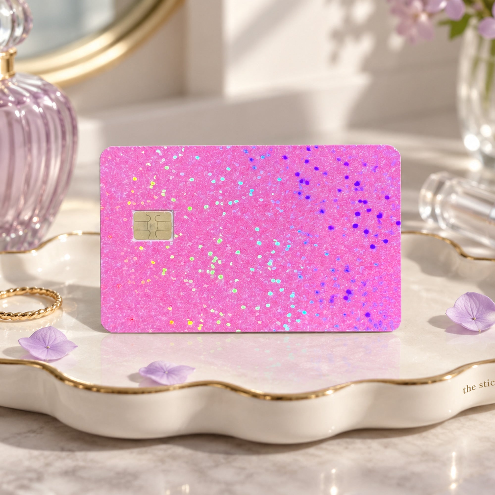 Pink glitter card skin on a scalloped trinket dish with perfume and a gold ring by The Sticker Era