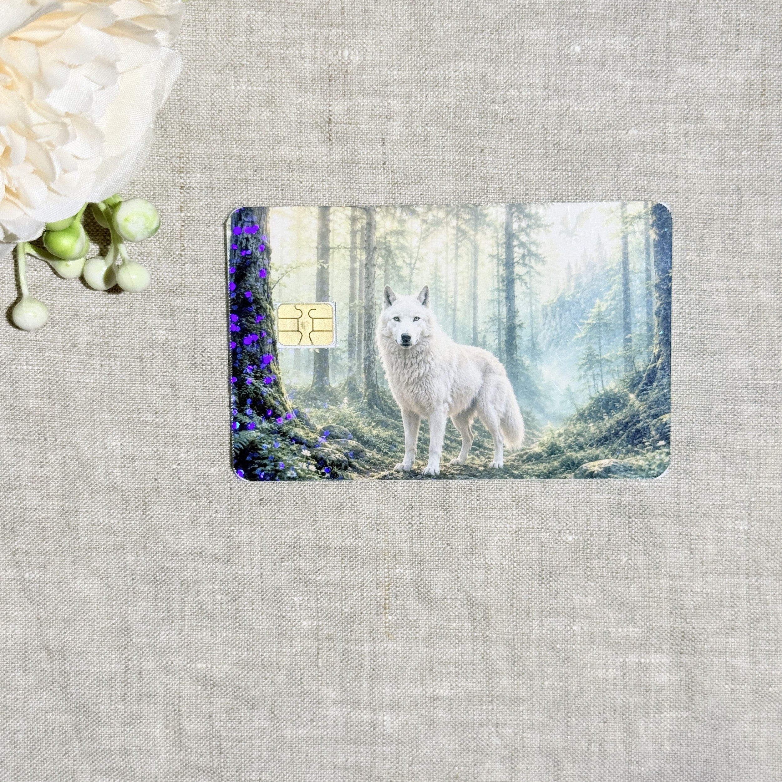 Misty forest wolf card skin with a white wolf standing in sunlit mossy woods on a debit card by The Sticker Era