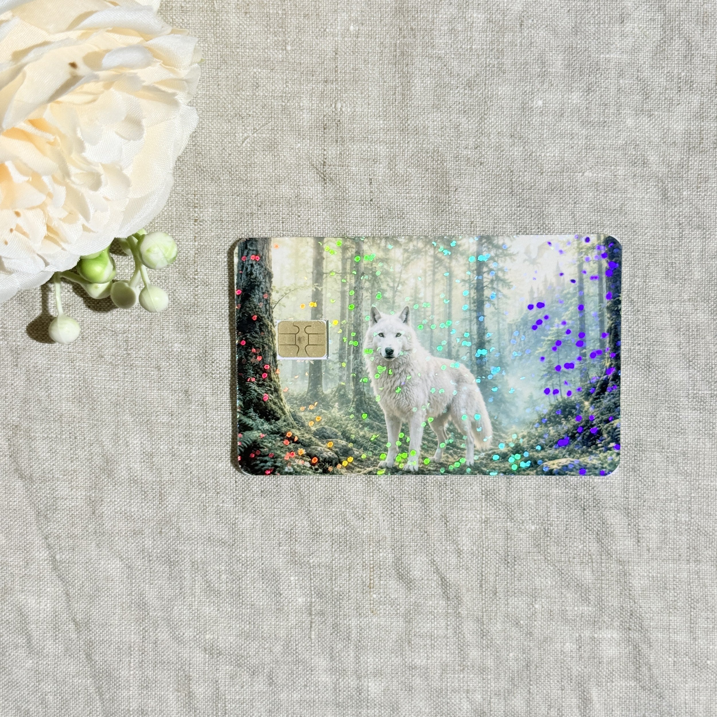 Close-up of holographic sparkle over the mossy trees and white wolf on the card skin by The Sticker Era