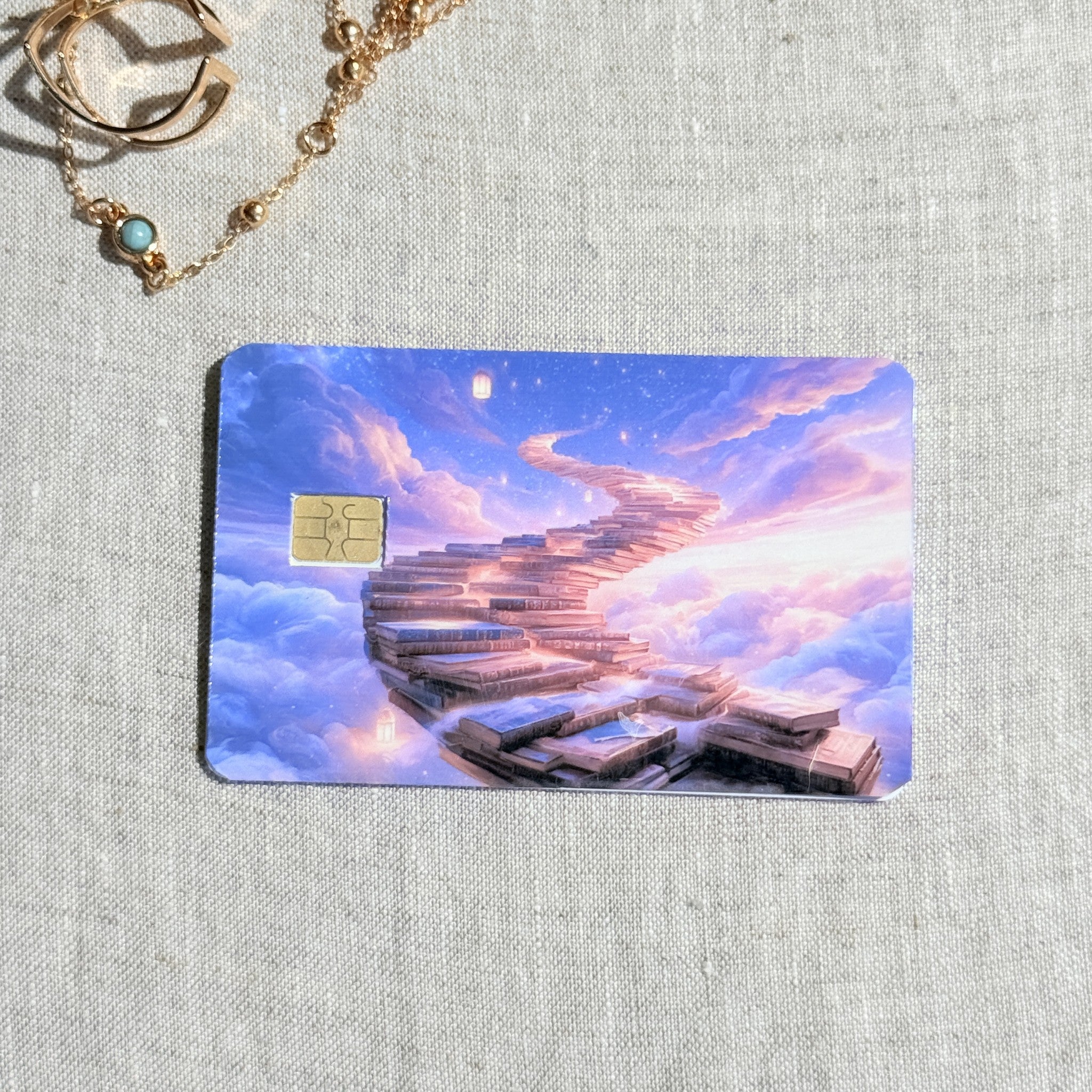 Book staircase card skin on a debit card, a staircase of books curving into a pink and violet sky