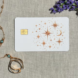 Celestial stars card skin on a debit card, copper stars and a crescent moon on white