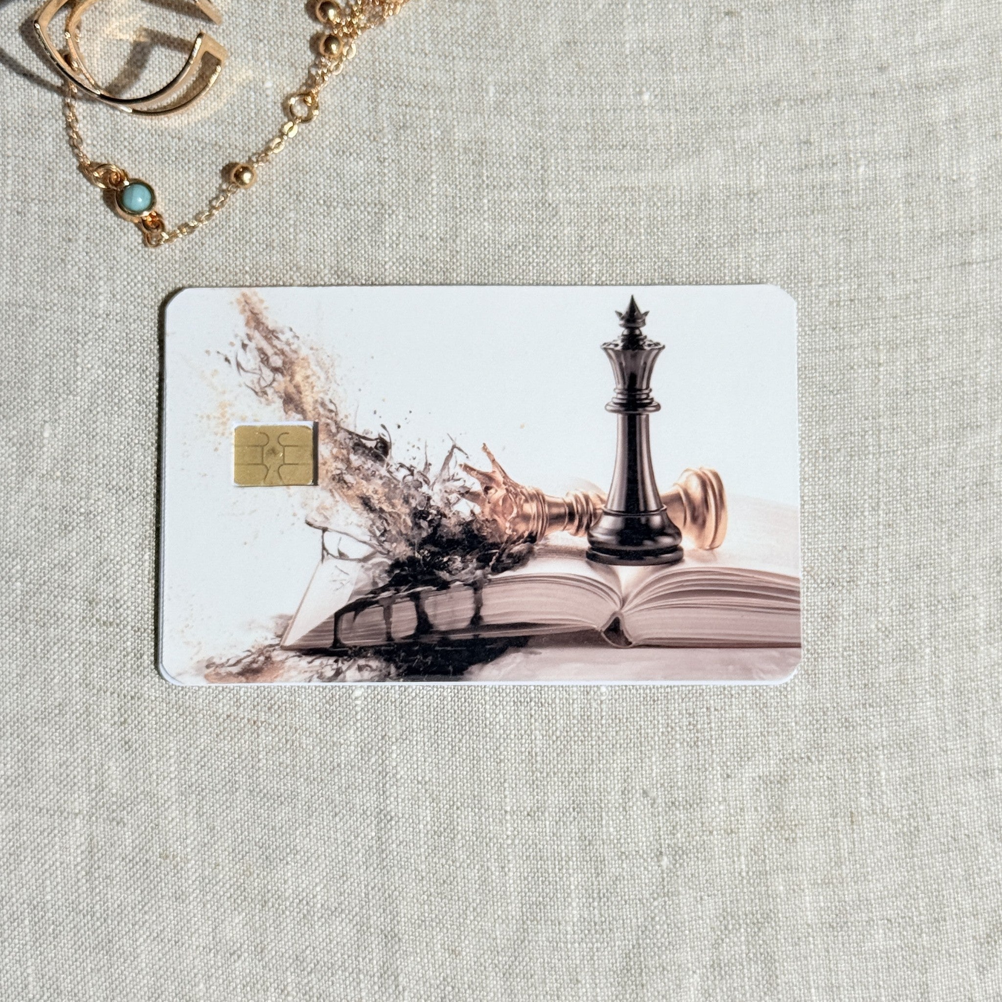 Chess king card skin on a debit card, black king on an open book dissolving into pieces