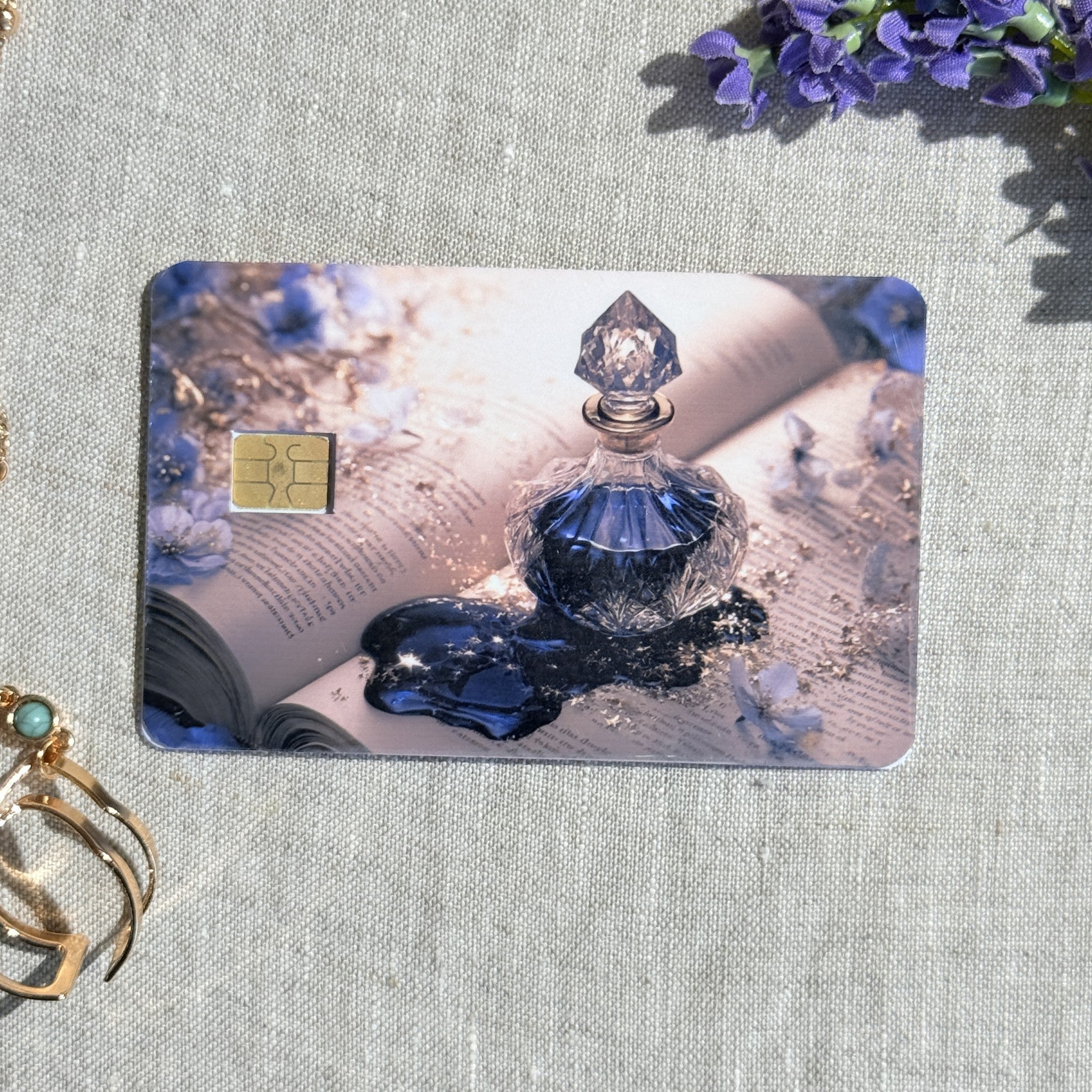 Midnight perfume card skin on a debit card, deep blue crystal bottle on an open book