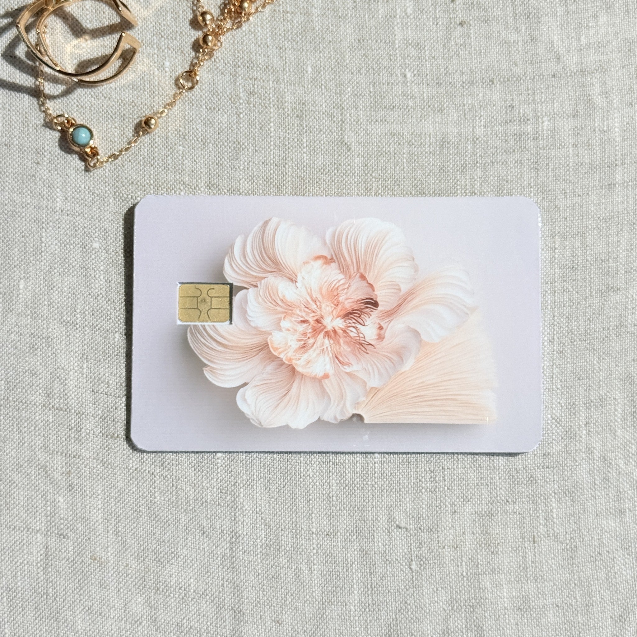 Peony card skin on a debit card, a single sculpted blush peony on clean white