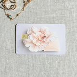 Soft blush bloom debit card sticker shown flat on linen