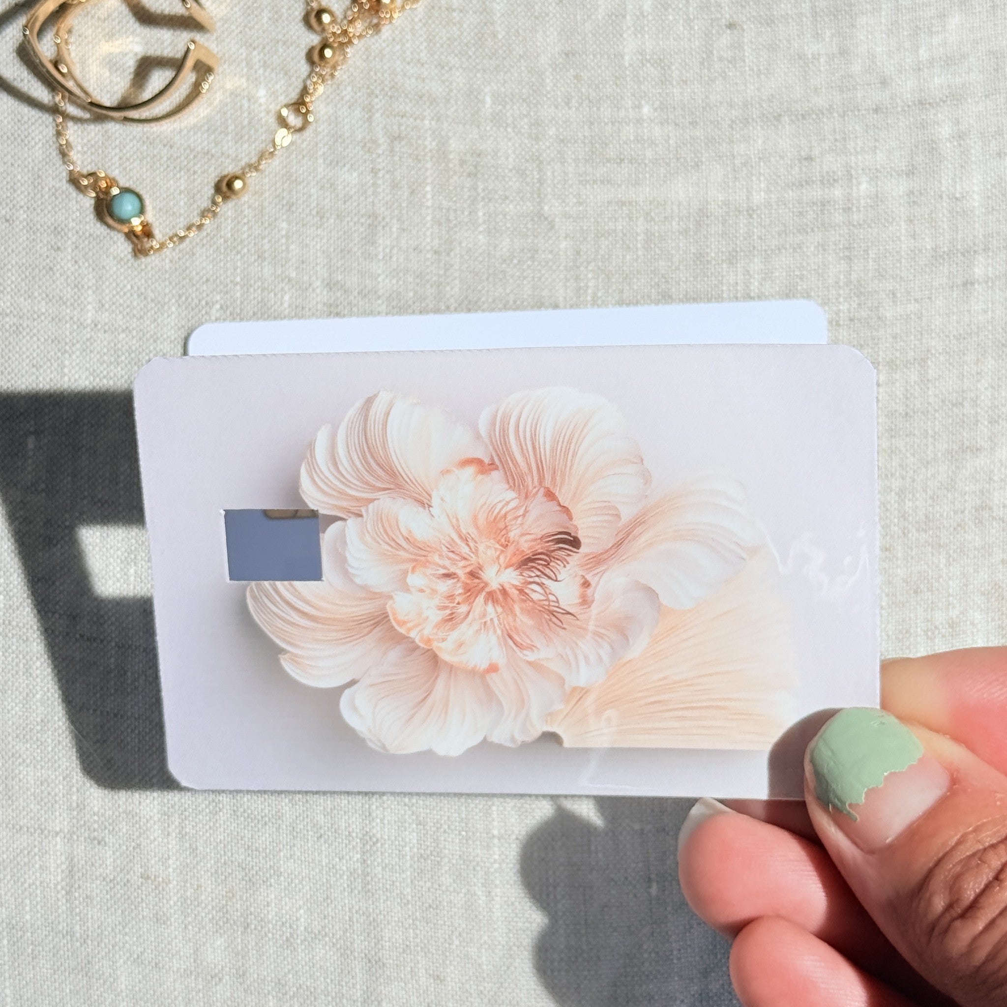 Peony card skin held in hand for scale