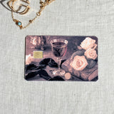 Wine and roses card skin on a debit card, carved goblet and blush roses on dark velvet