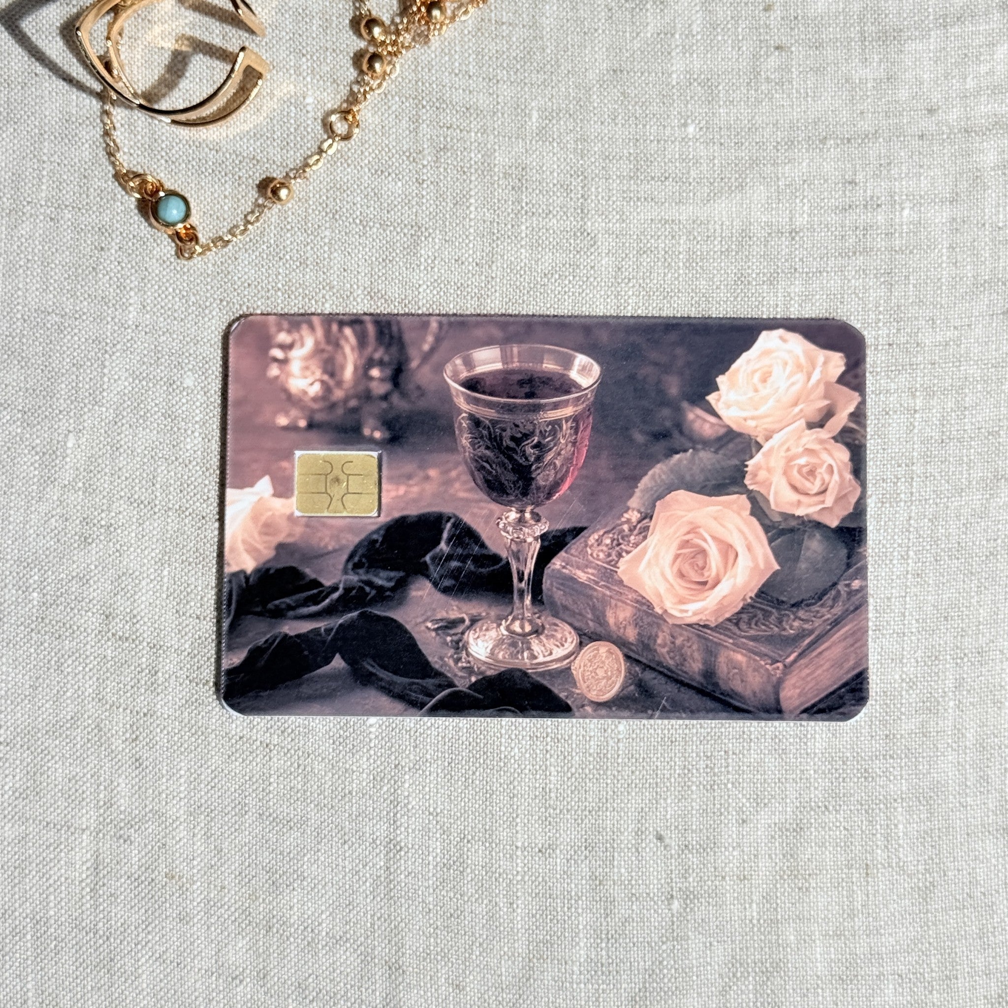 Wine and roses card skin on a debit card, carved goblet and blush roses on dark velvet