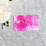 Pink marble card skin with gold veins and holographic sparkle on a debit card by The Sticker Era