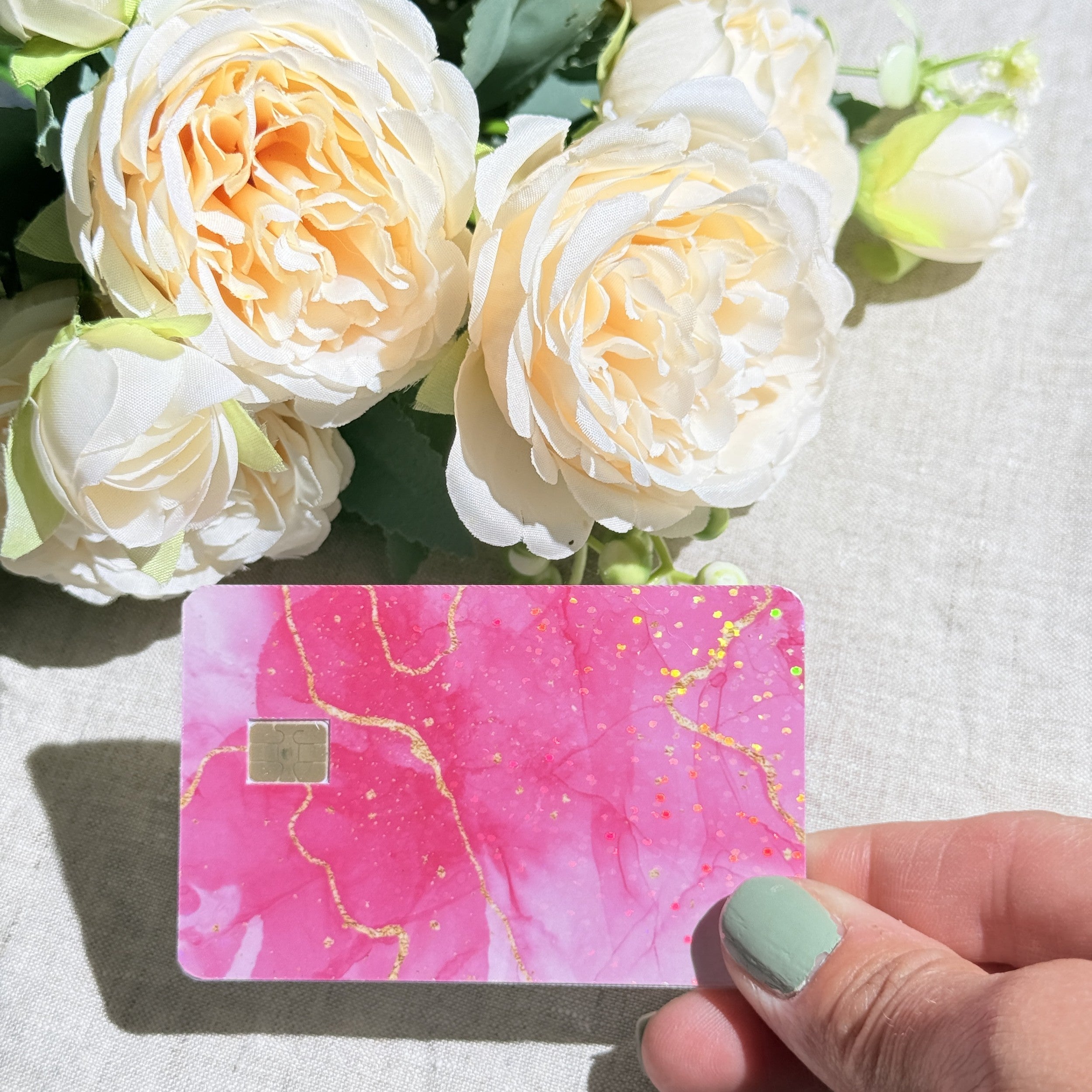Hand holding the pink marble debit card skin in sunlight by The Sticker Era