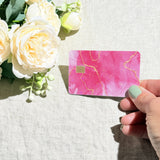 Pink marble card skin held at an angle by The Sticker Era