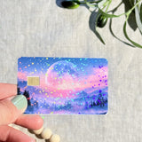 Hand holding the pink moon mountain holographic card skin catching the light by The Sticker Era