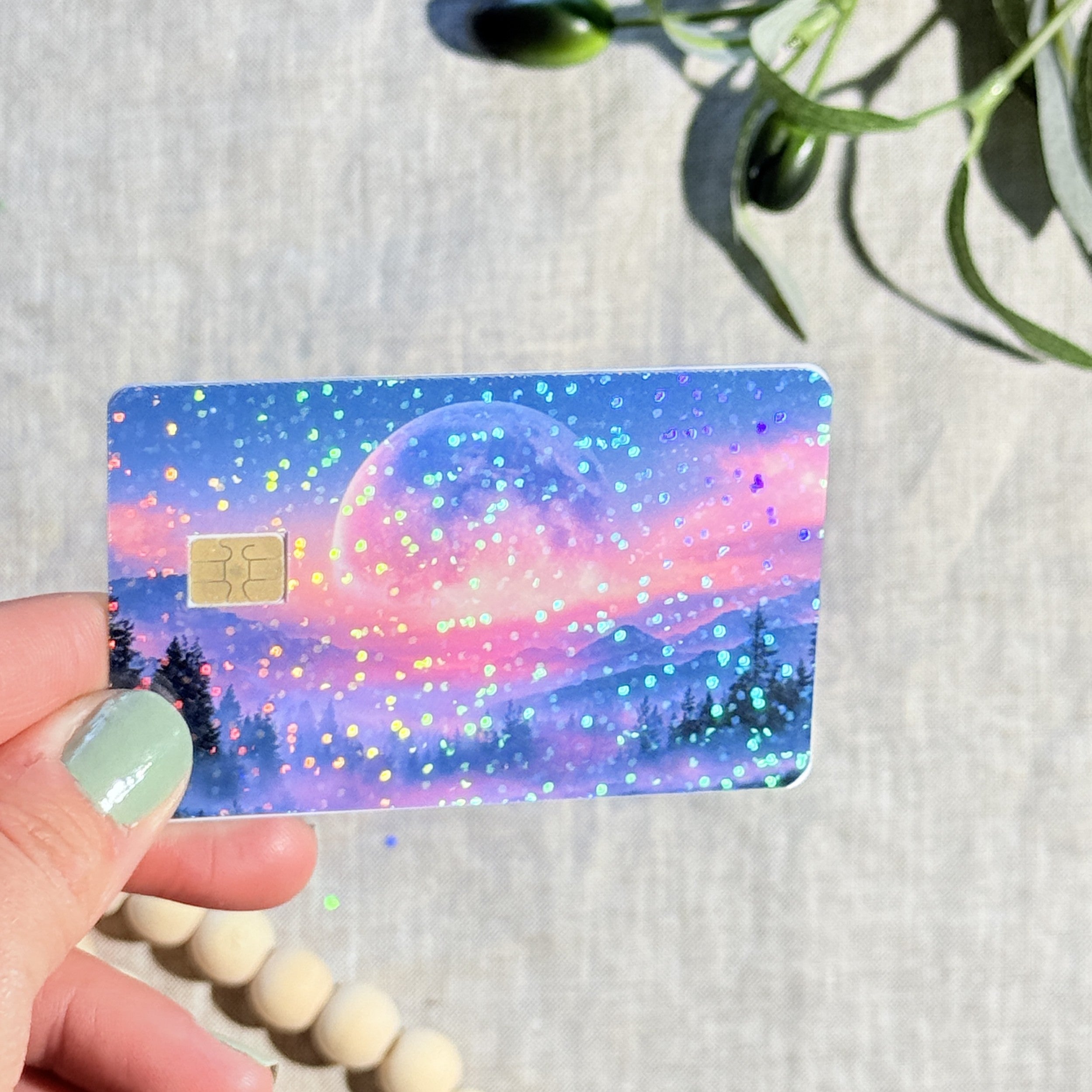 Pink moon mountains sparkle debit card skin held in sunlight by The Sticker Era