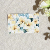Plumeria card skin with cream and yellow tropical flowers on sage leaves on a debit card by The Sticker Era