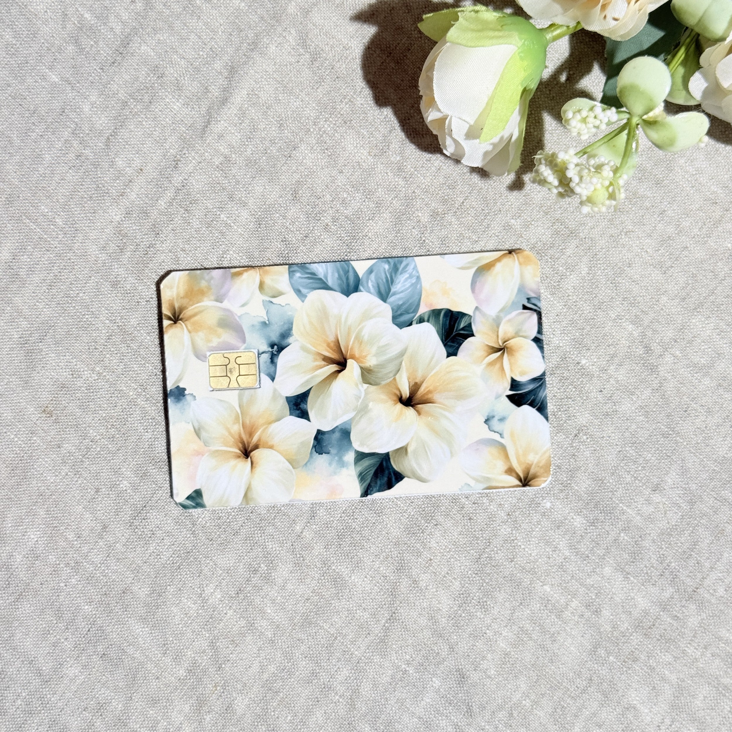 Close-up of cream plumeria blooms and sage leaves on the card skin by The Sticker Era