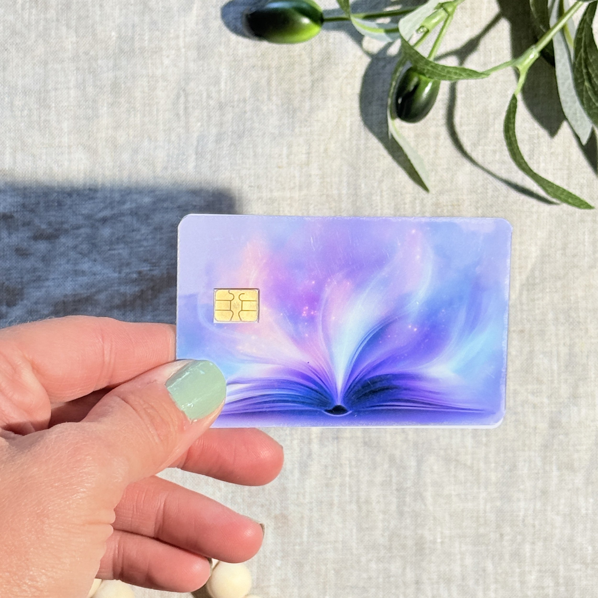 Hand holding the lavender magic book card skin in sunlight by The Sticker Era