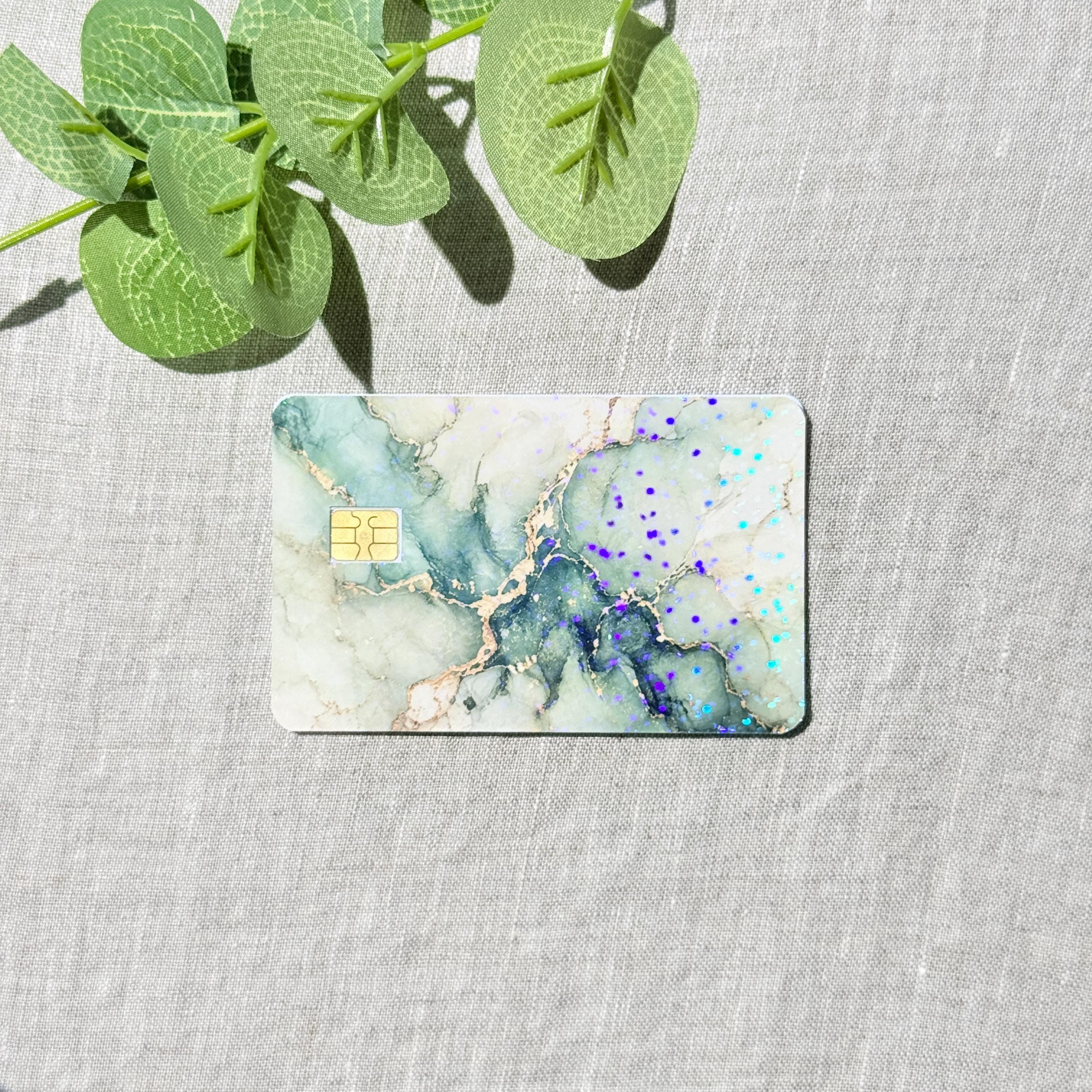 Sage green marble card skin with gold veins and holographic flecks on gray linen with eucalyptus by The Sticker Era