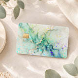 Green marble debit card skin on cream linen with eucalyptus leaves by The Sticker Era