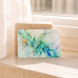 Hand holding the sage green marble card skin at a card reader by The Sticker Era