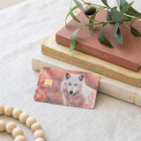 Wolf card skin on a debit card stacked on vintage books with greenery by The Sticker Era