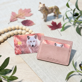 White wolf card skin on a debit card beside a blush pink cardholder with fall maple leaves by The Sticker Era