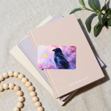 Whimsigoth raven card skin resting on stacked pastel notebooks by The Sticker Era