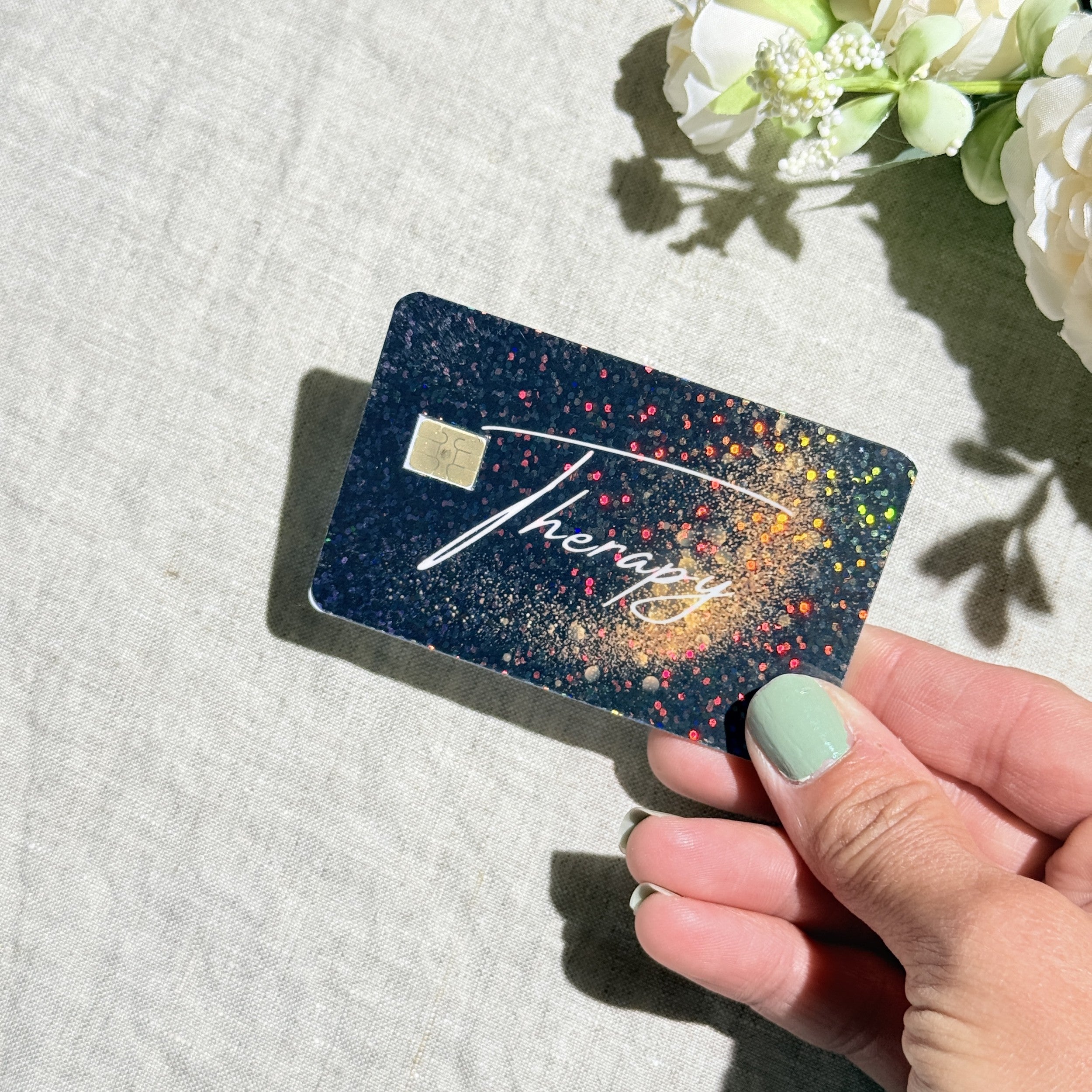 Hand holding the Therapy debit card skin in sunlight by The Sticker Era