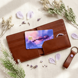 Nebula violin card skin on open brown leather wallet with pearl bracelet, keychain and petals BY THE STICKER ERA