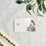 Wolf reader card skin with a girl reading beside a white wolf on a cream debit card by The Sticker Era