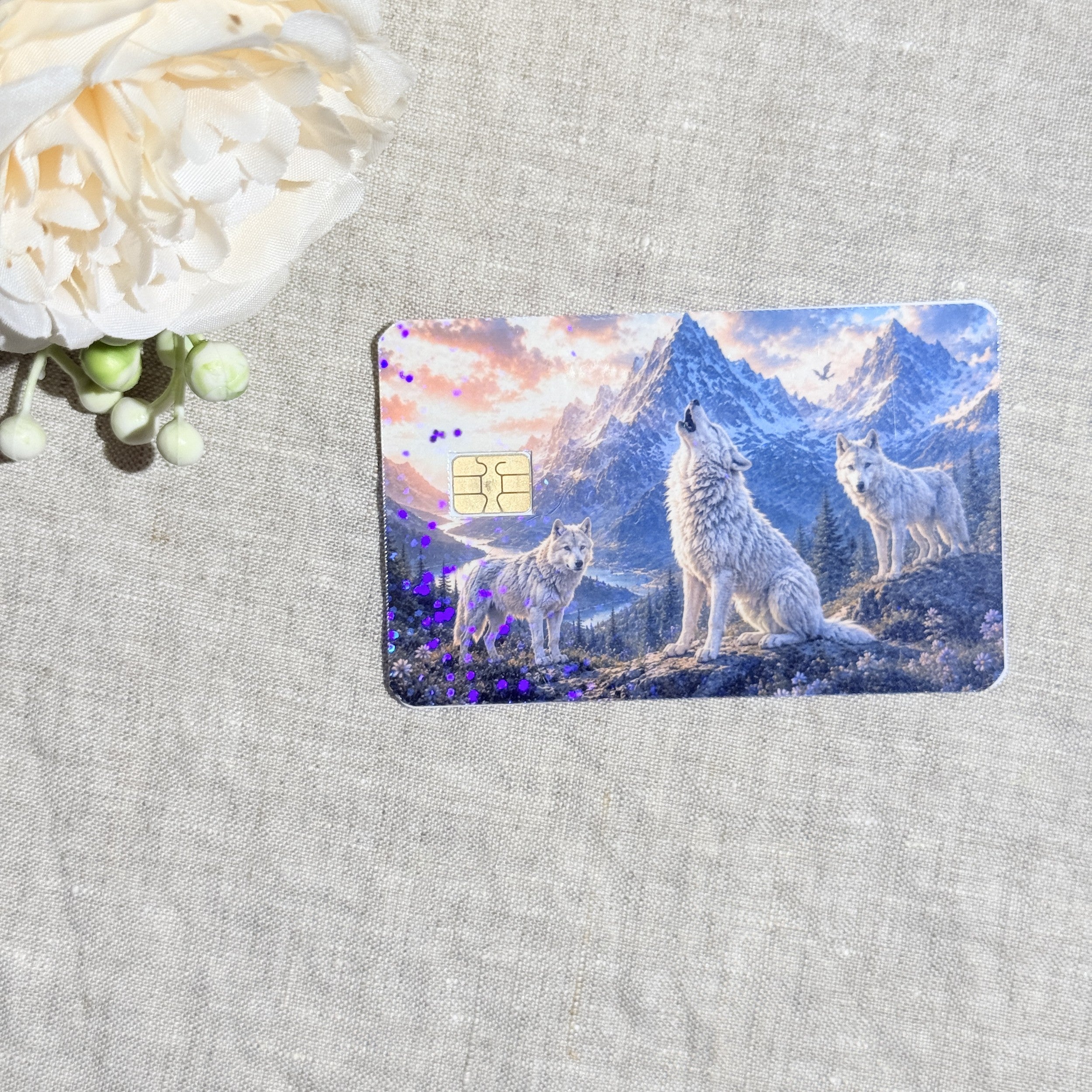 Wolf pack card skin with three white wolves howling under snowy mountains on a debit card by The Sticker Era